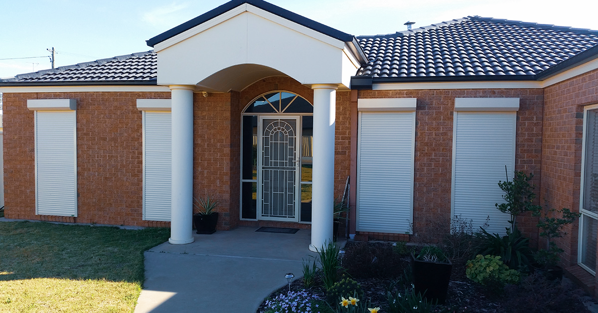 Brick house with white roller shutters