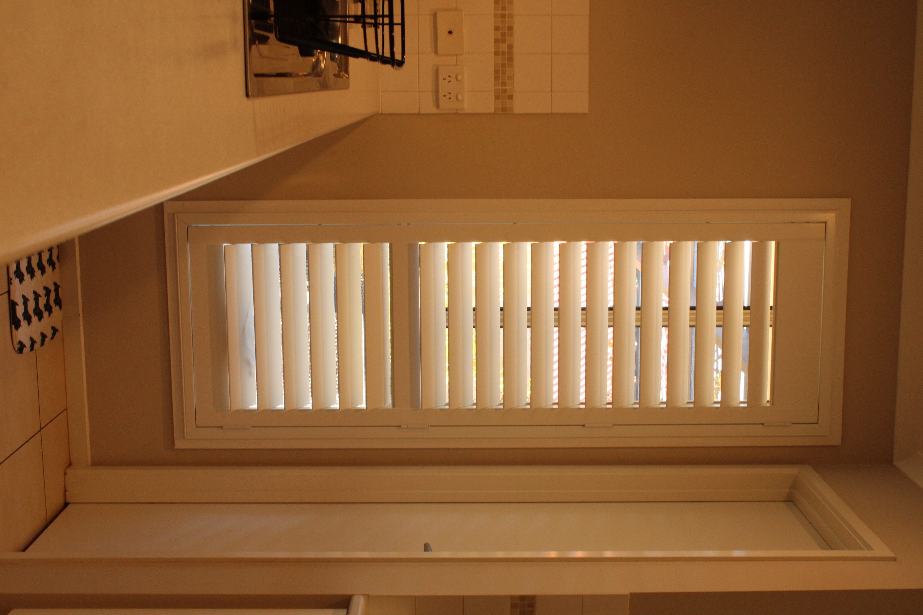 White plantation shutters above a kitchen sink