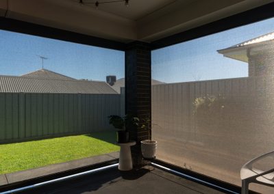 View from inside an alfresco through a mesh outdoor blind to the garden