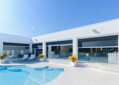 Dark outdoor blinds on a modern white home beside a swimming pool