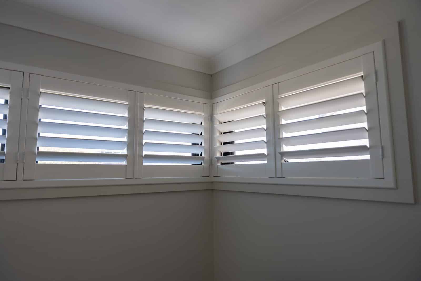 White plantation shutters fitted to corner windows in a lounge room