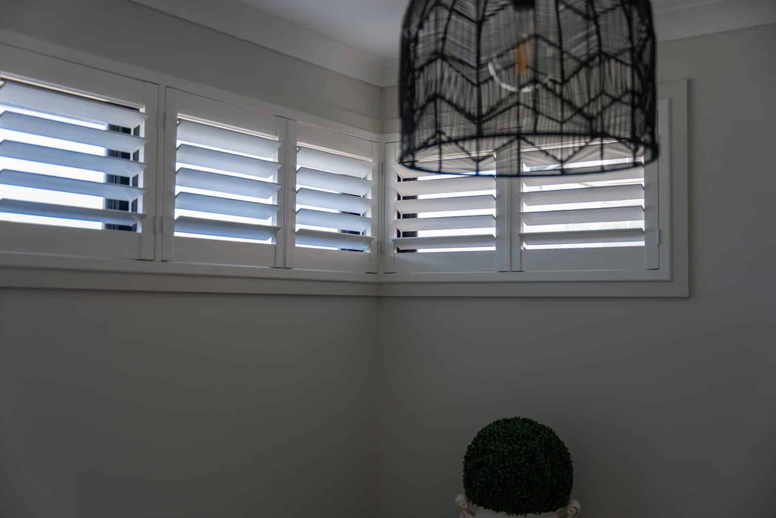 White plantation shutters across living room windows White plantation shutters across living room windows