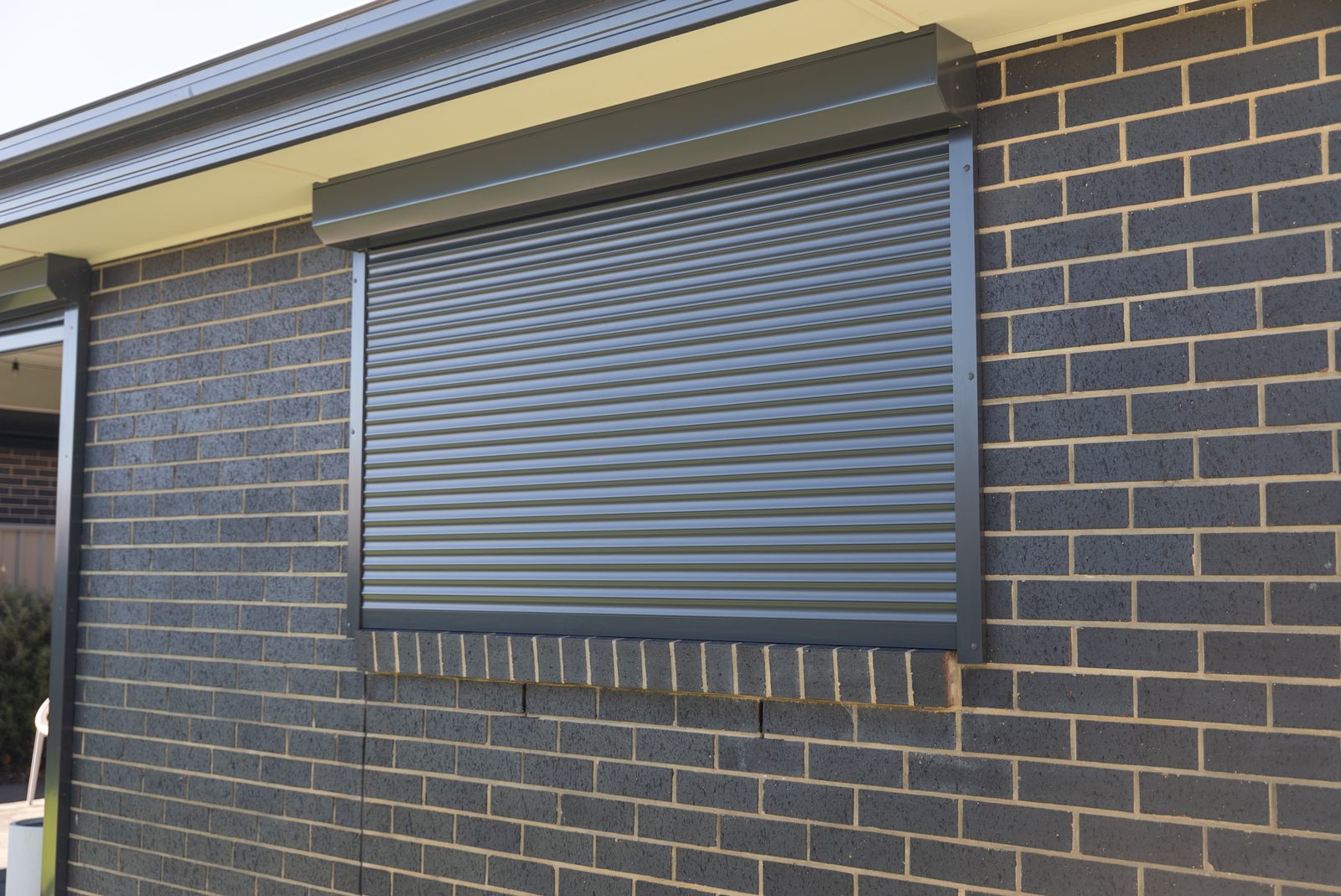 Roller shutter fitted above a window on a dark brick home Roller shutter fitted above a window on a dark brick home