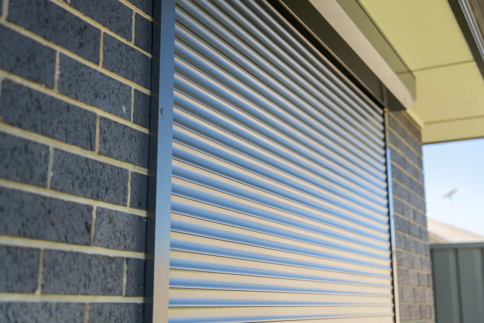 Close-up of closed roller shutter slats on a brick home