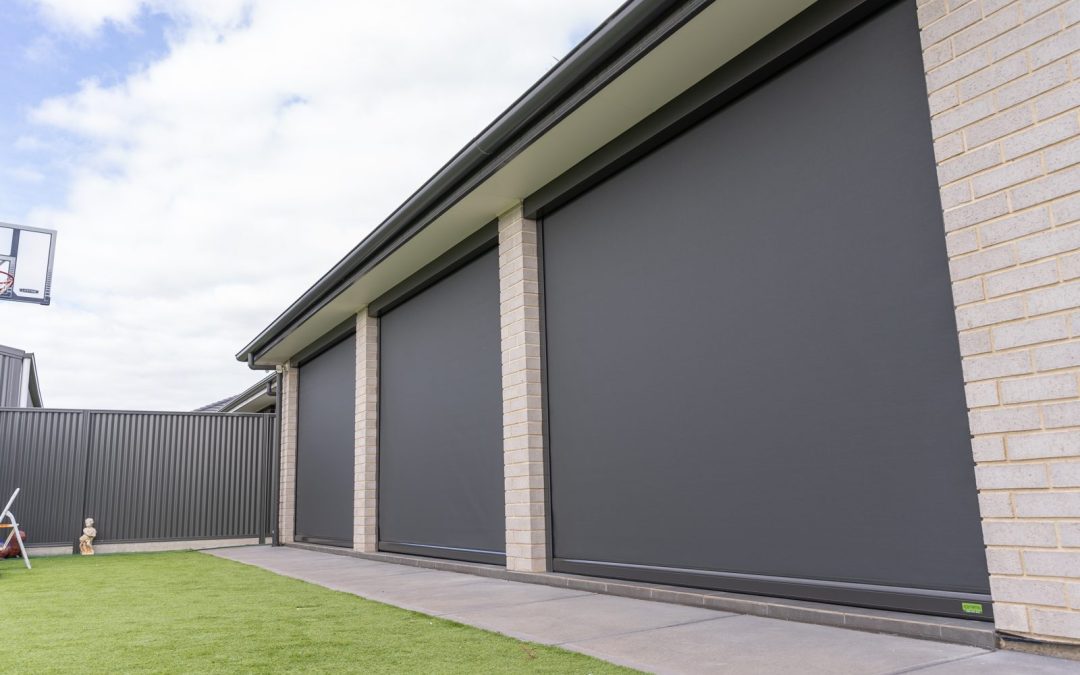 Charcoal track-guided outdoor blinds closed between brick pillars on an alfresco