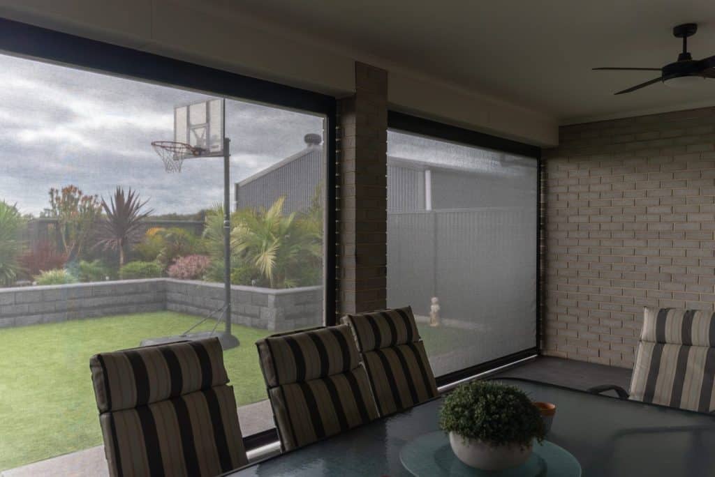 View from inside an alfresco through track-guided mesh outdoor blinds to the garden