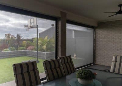 View from inside an alfresco through track-guided mesh outdoor blinds to the garden